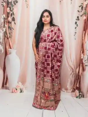 Grace in Maroon – This exquisite wine-toned saree is adorned with golden zari checks and intricate multicolored motifs, finished with a beautifully woven heritage border. A timeless drape that blends royal charm with festive elegance, perfect for weddings, cultural celebrations, and special occasions